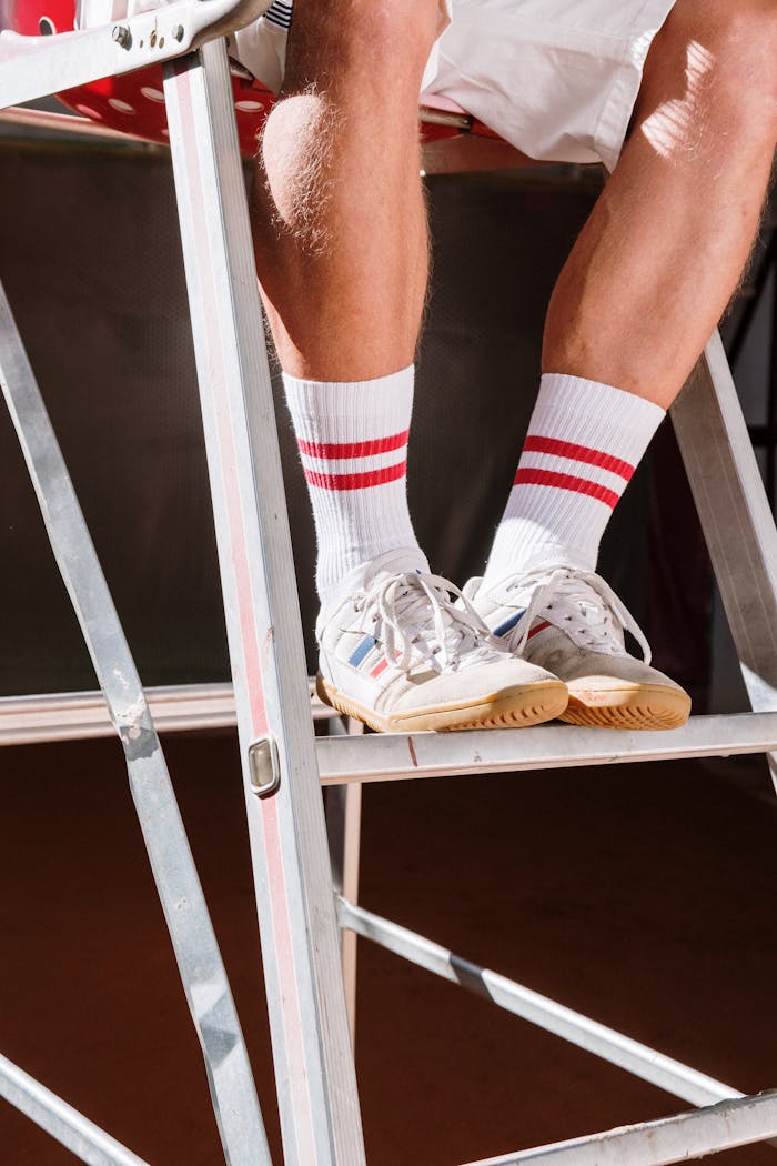 gallery-5 Close-up of sneakers and socks on a metal ladder in bright sunlight, emphasizing casual style.