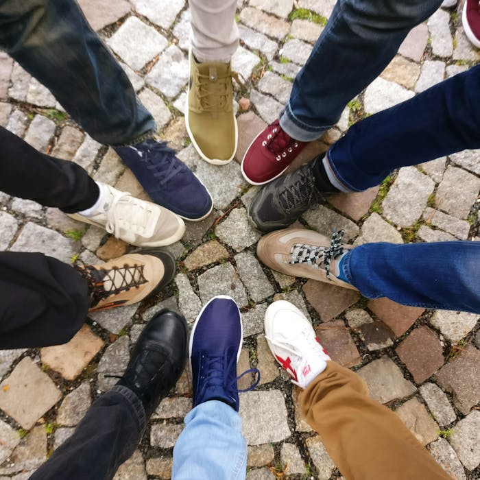 gallery-4 Circle of sneakers on cobblestone pavement representing diversity and urban fashion.